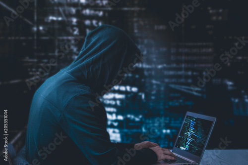 Anonymous hacker with laptop in front of binary code cyber security