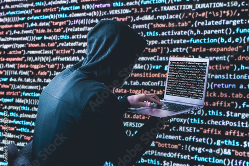 Anonymous hacker with laptop in front of binary code cyber security