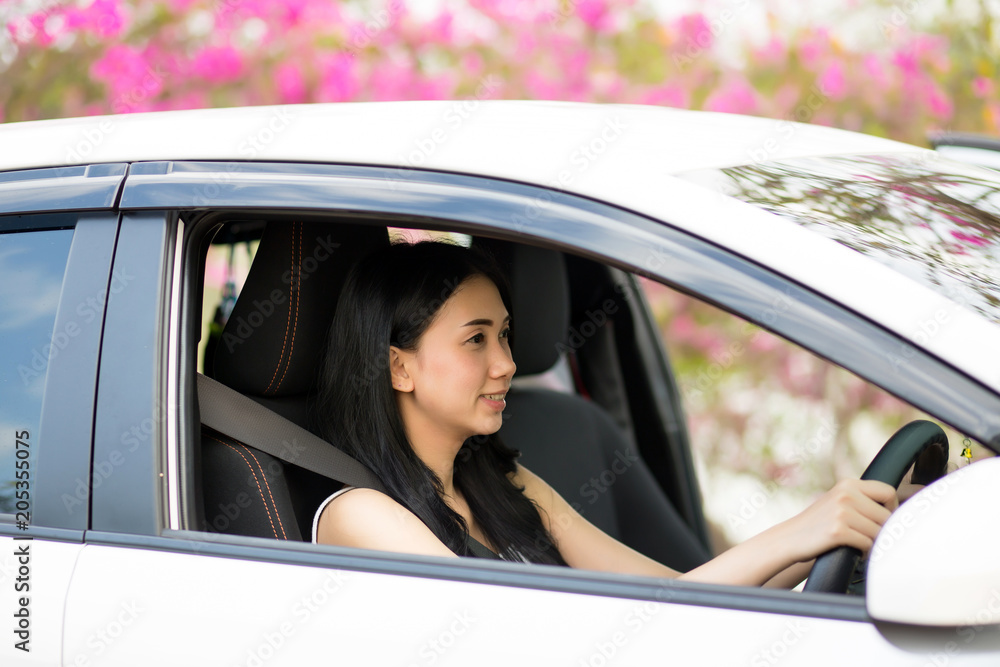 Pretty Asian women in a white car happy driving