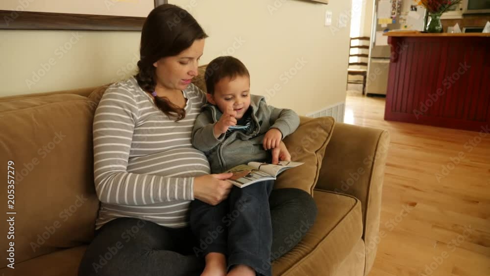 A pregnant mother reading a book with her toddler