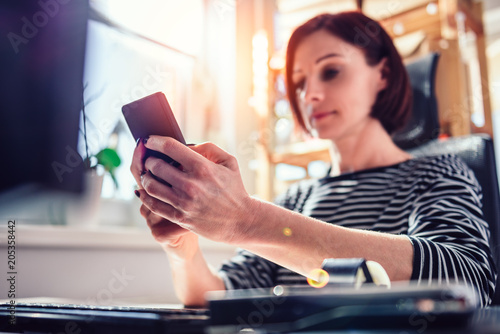 Woman using smart phone at the office