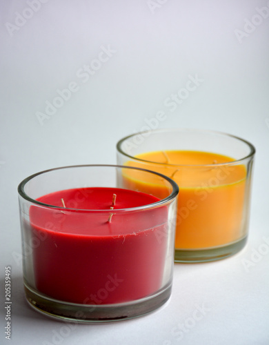 two candles isolated (red and yellow) in transparent glasses.in the foreground is a red