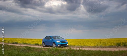 GOMEL, BELARUS - May 15, 2018: blue car parked in the field against a stormy sky. photo