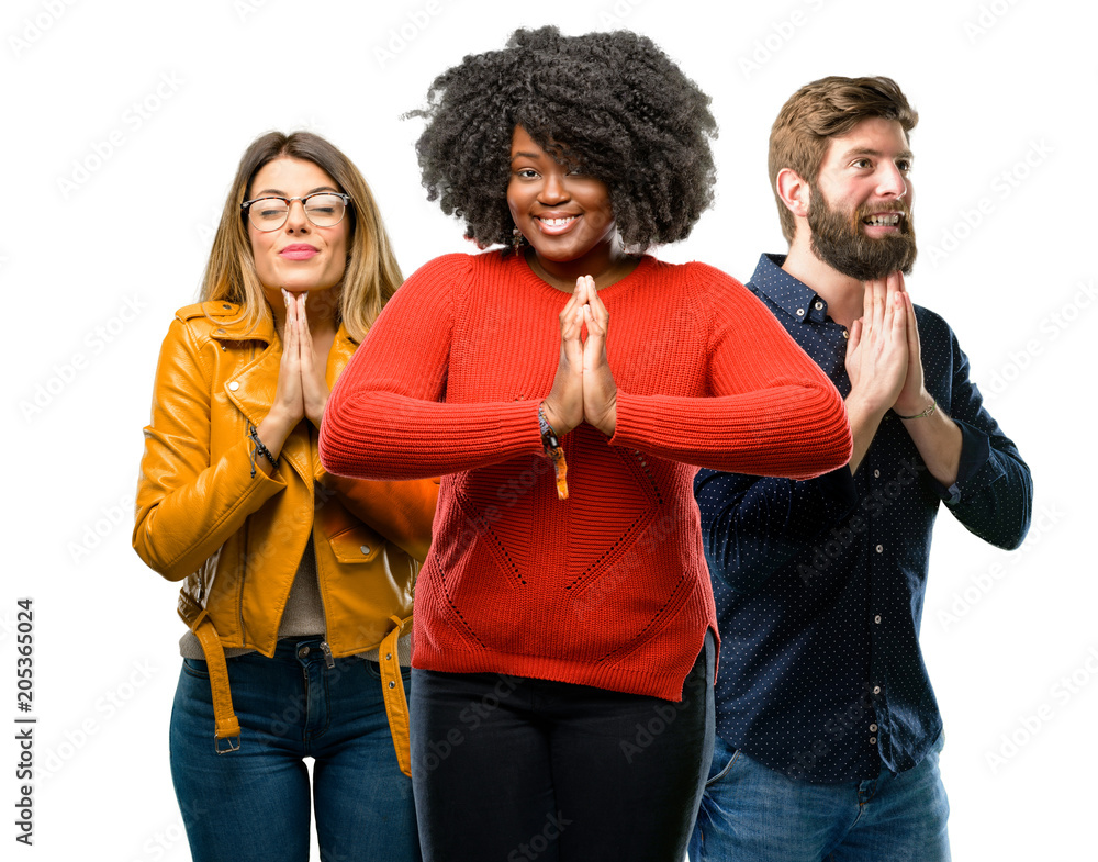 Group of three young men and women with hands together in praying gesture, expressing hope and please concept Group of three young men and women with hands together in praying gesture, expressing hope and please concept