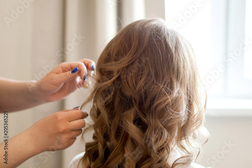 Hairdresser making curly haircut, beauty saloon.