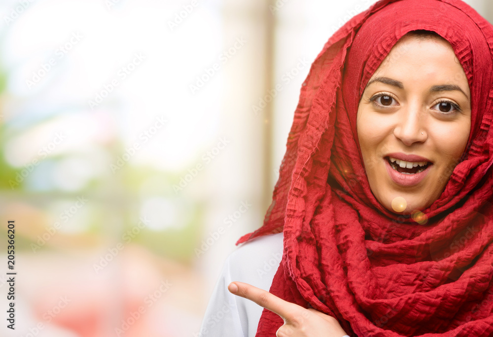 Young arab woman wearing hijab pointing away side with finger Young arab woman wearing hijab pointing away side with finger