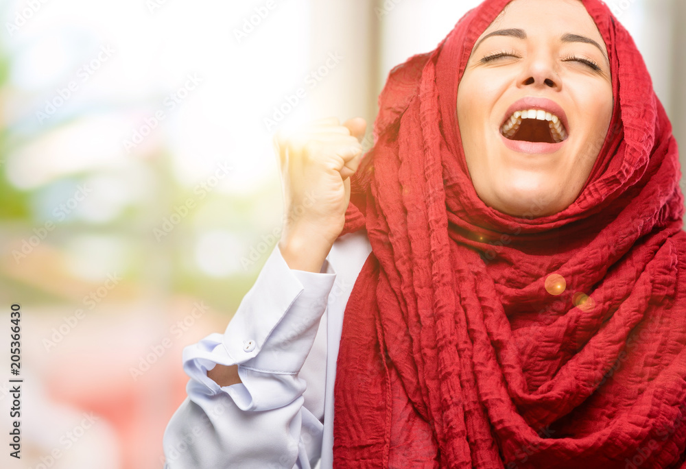 Young arab woman wearing hijab happy and excited expressing winning gesture. Successful and celebrating victory, triumphant Young arab woman wearing hijab happy and excited expressing winning gesture. Successful and celebrating victory, triumphant