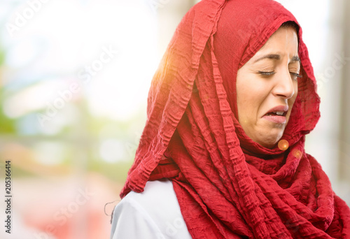 Young arab woman wearing hijab crying depressed full of sadness expressing sad emotion