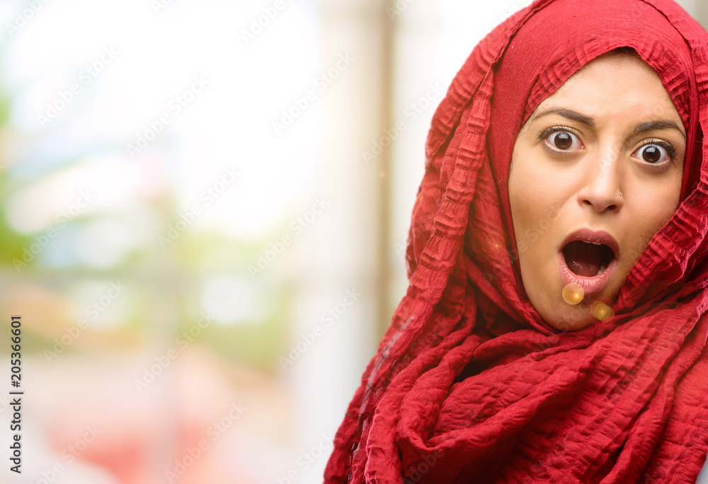 Young arab woman wearing hijab scared and surprised cheering expressing wow gesture. Unbelieving Young arab woman wearing hijab scared and surprised cheering expressing wow gesture. Unbelieving