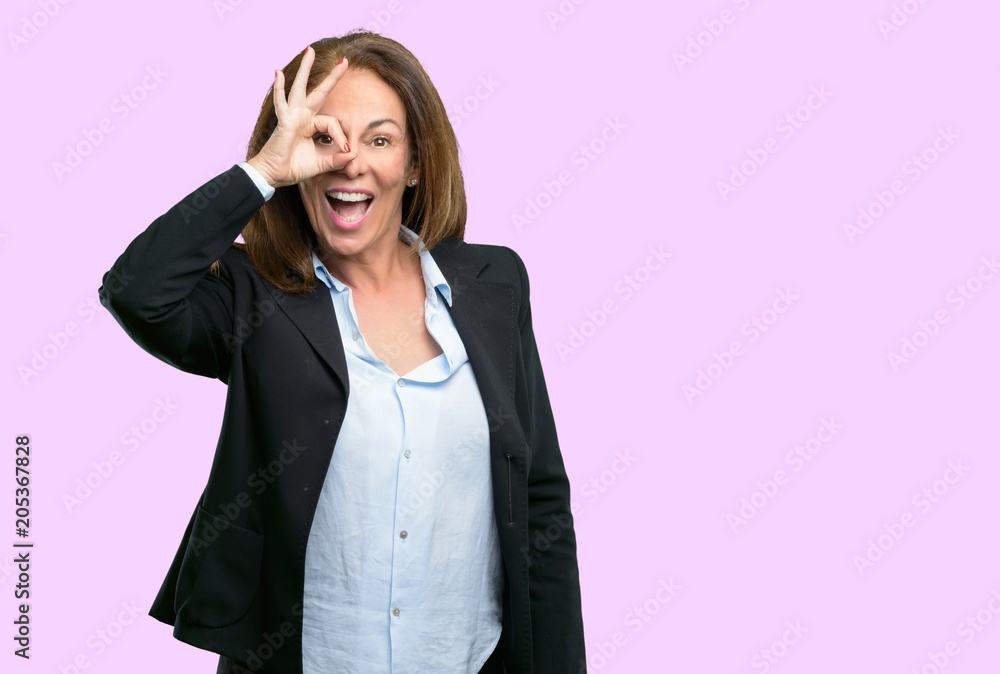 Middle age business woman looking at camera through her fingers in ok gesture. Imitating binoculars, beautiful eyes and smile Middle age business woman looking at camera through her fingers in ok gesture. Imitating binoculars, beautiful eyes and smile