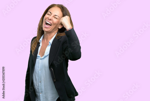 Middle age business woman happy and excited expressing winning gesture. Successful and celebrating victory, triumphant