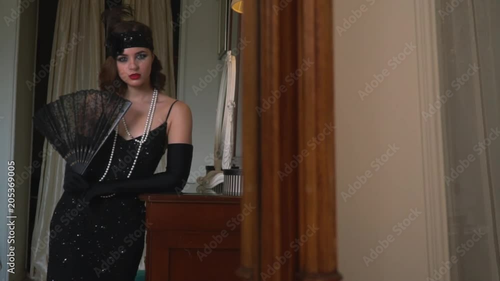 A young lady looks at herself in the mirror before going out to a party in the 1920s A young lady looks at herself in the mirror before going out to a party in the 1920s