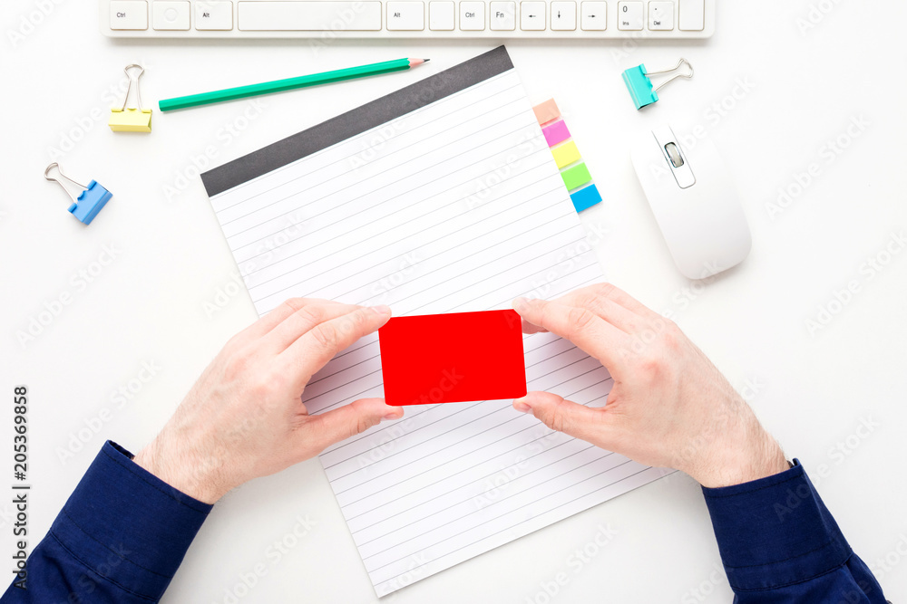 white desktop, male hands, guy holding a business card, pensil, notebook, white background with copy space, for advertisement, top view white desktop, male hands, guy holding a business card, pensil, notebook, white background with copy space, for advertisement, top view