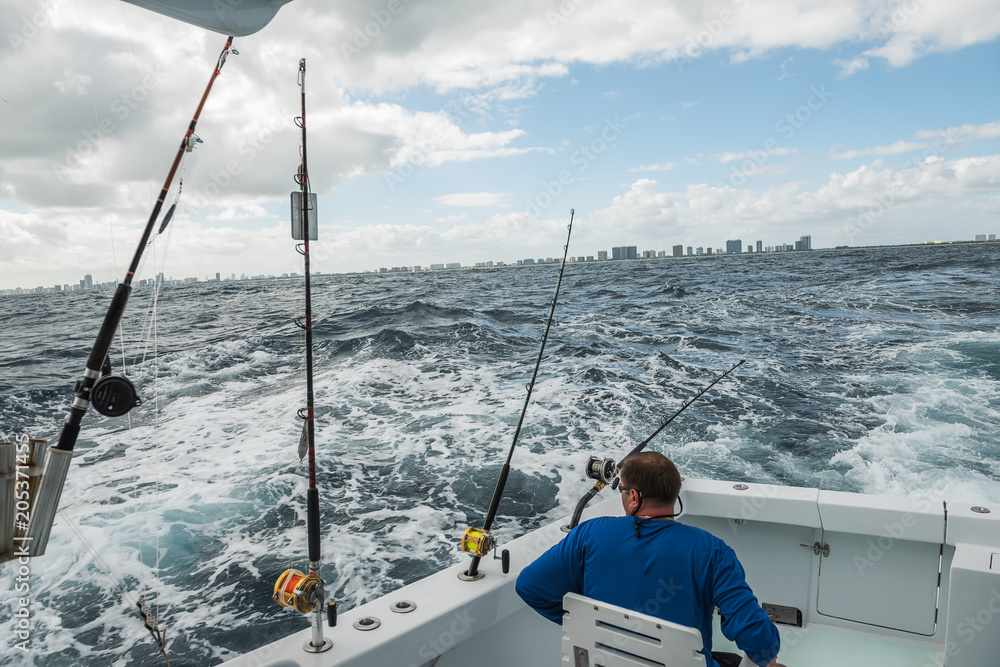 A man in a fishing boat in a stormy ocean with a view of the coast of Miami. fishing in Florida. USA.
