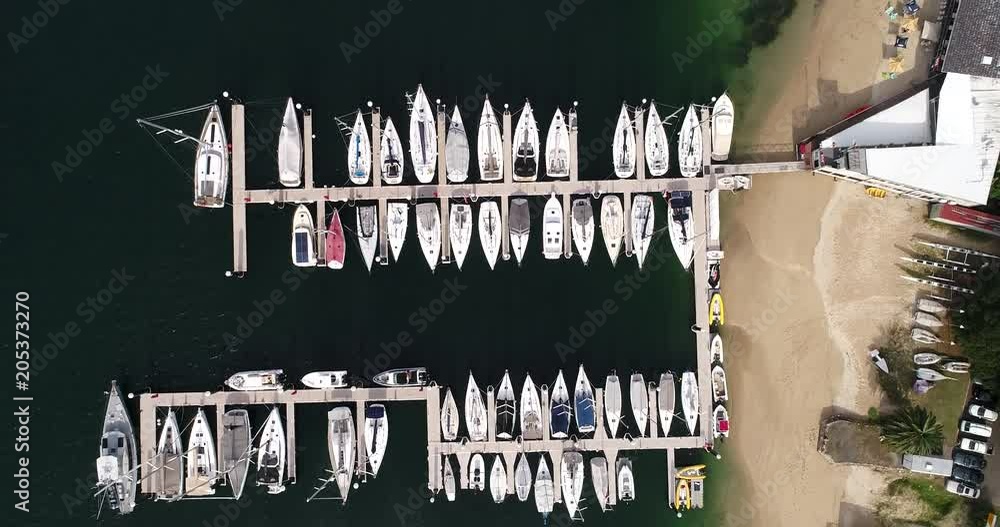 Top down view over jetties and the spit yacht sailing club with yachts and boats moored in shallow waters on Sydney’s middle harbour.
Top down view over jetties and the spit yacht sailing club with yachts and boats moored in shallow waters on Sydney’s middle harbour.