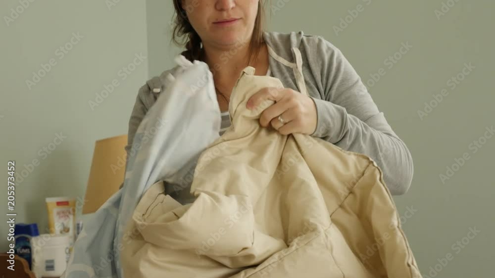 Pregnant mother makes the bed in her bedroom after washing the sheets