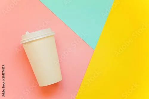 Obraz Papierowa filiżanka kawy na niebieskim, żółtym i różowym pastelowym kolorowym papierowym geometrycznym mieszkaniu nieatutowym tle. Pojemnik na napoje na wynos. Szablon kubka do picia do projektowania makiety tekstu, obrazu i logo