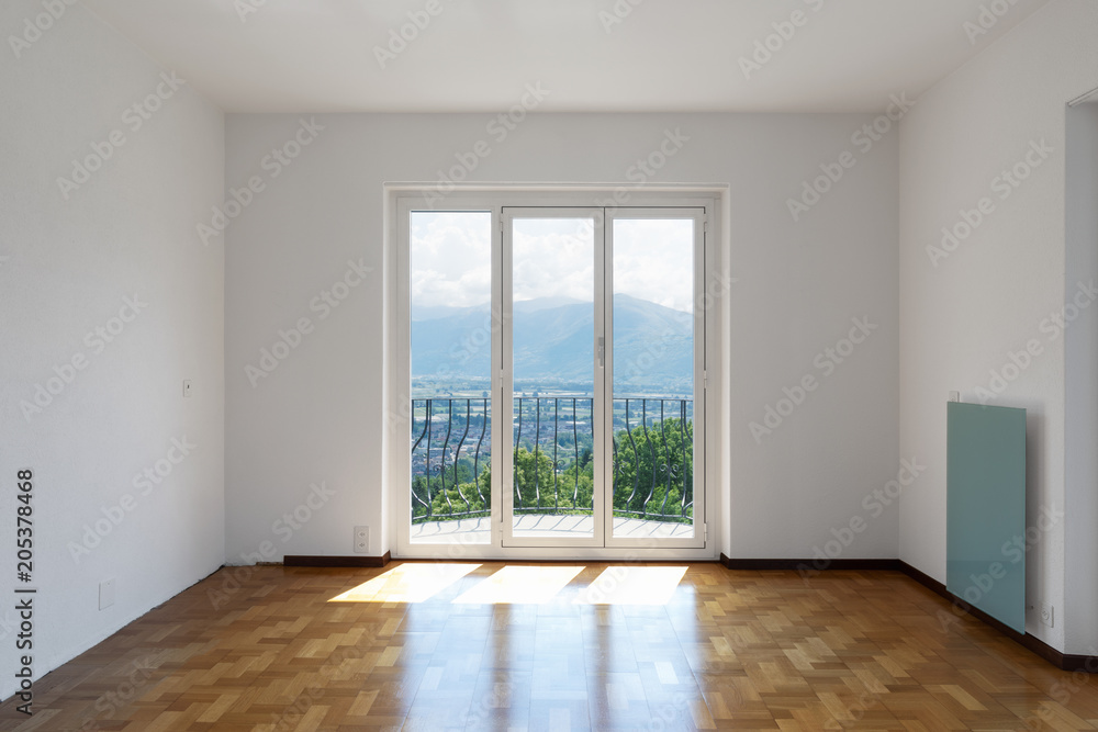 Empty white room with hardwood floors and large windows overlooking the Swiss hills Empty white room with hardwood floors and large windows overlooking the Swiss hills