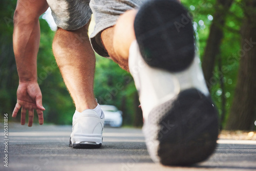 Outdoor cross-country running in concept for exercising, fitness and healthy lifestyle. Close up of feet of young runner man running along road in the park