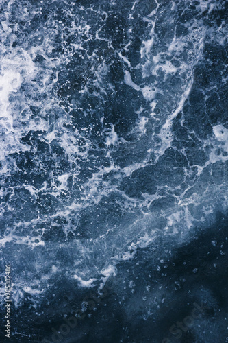 The surface of the sea with waves, splash, foam and bubbles at high tide, blue abstract background