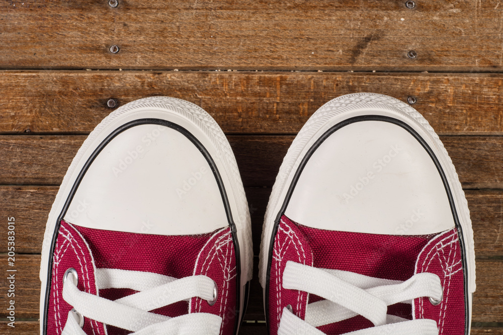 Pair of red sneakers on old retro wooden background. Close up. Retro fashion concept. Pair of red sneakers on old retro wooden background. Close up. Retro fashion concept.