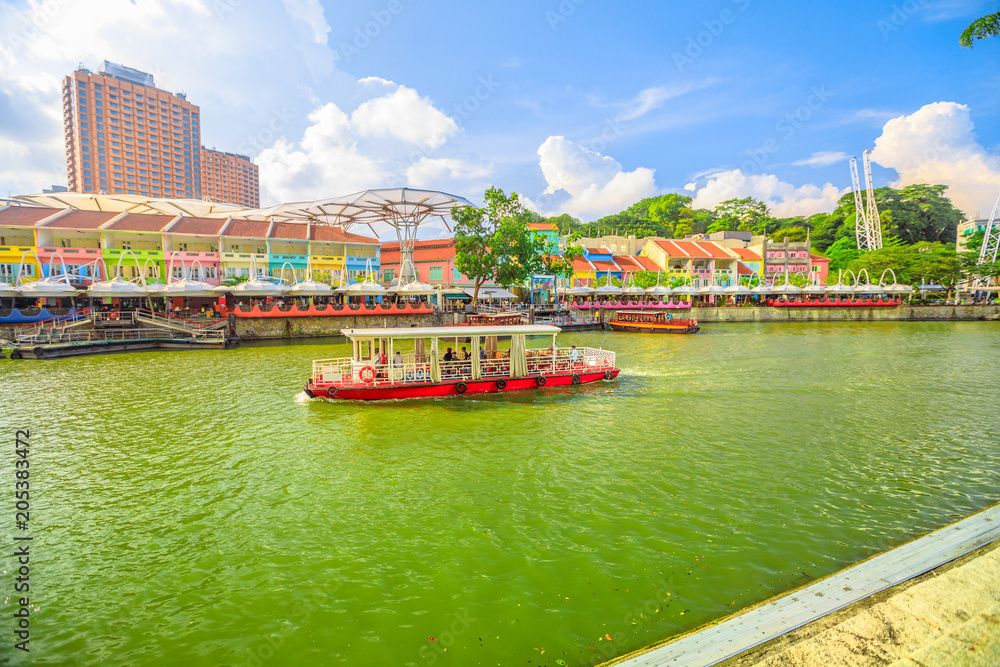 Naklejka premium Turystyczna łódź na rzece Singapur w okolicy Clarke Quay i Riverside w słoneczny dzień z błękitnym niebem. Singapur, Azja Południowo-Wschodnia.