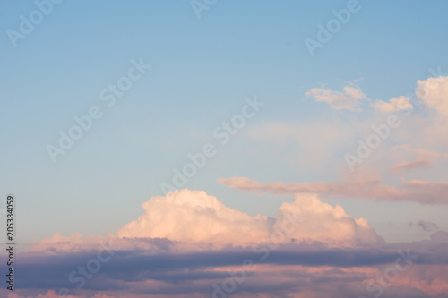 A blue cloudy sky. The reflection of yellow sun rays on the clouds during sunset © Oleksii Bulavin