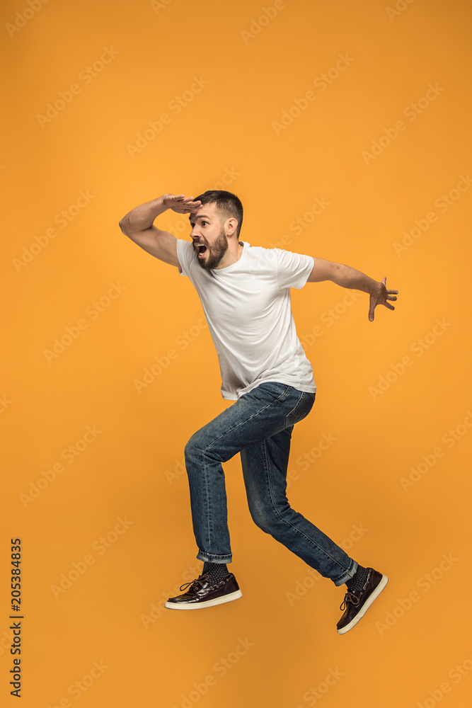 Freedom in moving. handsome young man jumping against orange background
