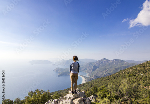 girl standing on a cliff in mountains near mediterranean sea