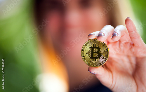 Female hand holding golden bitcoin coin, symbol of crypto currency