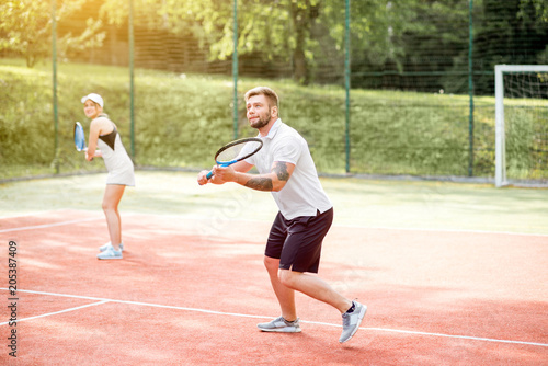 Young couple in white sports wear playing tennis on the tennis court outdoors © rh2010