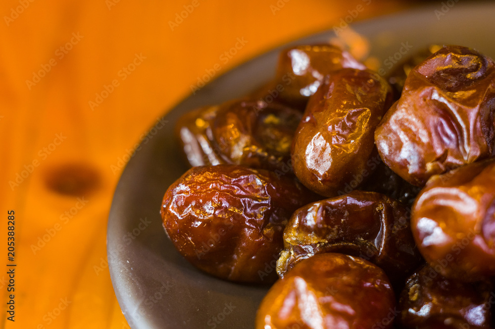 dried dates in a ceramic plate on a wooden table dried dates in a ceramic plate on a wooden table
