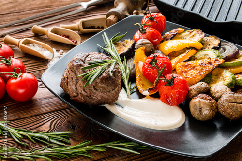 Steak chateaubriand, grilled vegetables, cherry tomatoes, rosemary, pepper beans, sea salt, grill pan on wooden background, photo