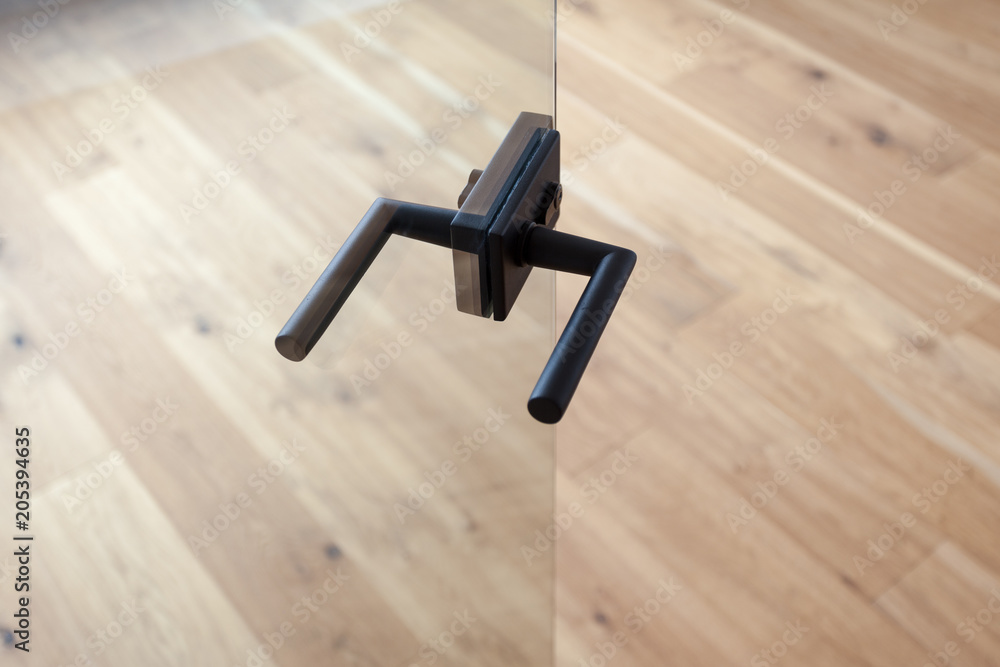 Fototapeta premium Glass door with metallic handle open in to the empty room with wooden floor