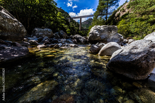 A Mountain River With Crystal Clear Waters Under A Bridge In Corsica