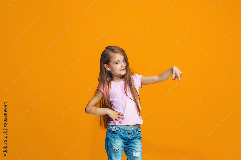The happy teen girl presenting something, half length closeup portrait on orange background. The happy teen girl presenting something, half length closeup portrait on orange background.
