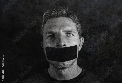 young man with mouth and lips sealed covered with adhesive tape in censorship coerced freedom of speech and forced silence and secrecy photo