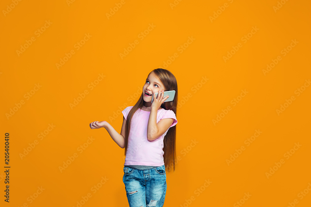 The happy teen girl standing and smiling with phone The happy teen girl standing and smiling with phone