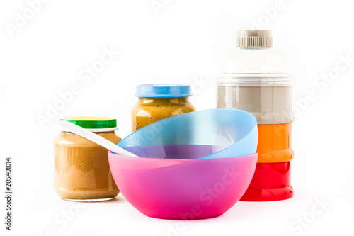 Baby food: Jar with fruit puree and colorful bowls isolated on white background