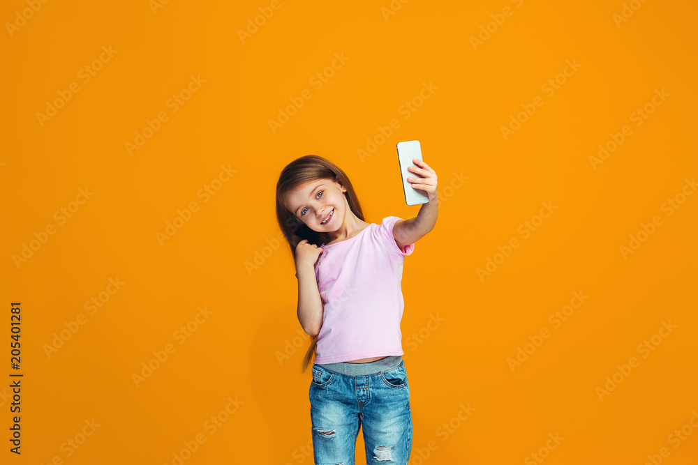 The happy teen girl standing and smiling with phone The happy teen girl standing and smiling with phone
