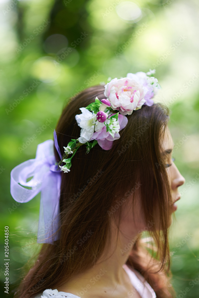 Naklejka premium Pretty young woman in a white dress walking in the forest