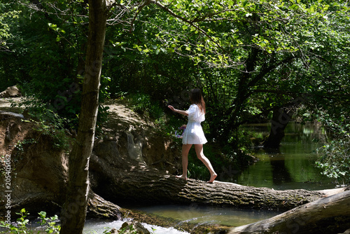 Pretty young woman in a white dress walking in the forest