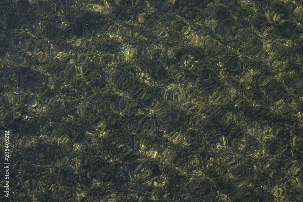 Textured wavy clear water over a dark bottom on a Summer day