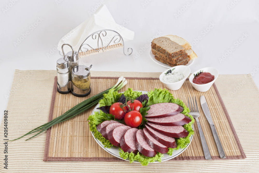 Smoked sausage with tomatoes and lettuce leaves on a plate. Smoked sausage with tomatoes and lettuce leaves on a plate.