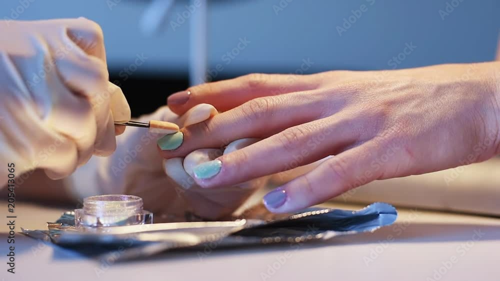 Nail master doing stylish trendy mirror manicure on female nails in beauty salon. Metal nail art. Chrome nails. Nail master doing stylish trendy mirror manicure on female nails in beauty salon. Metal nail art. Chrome nails.