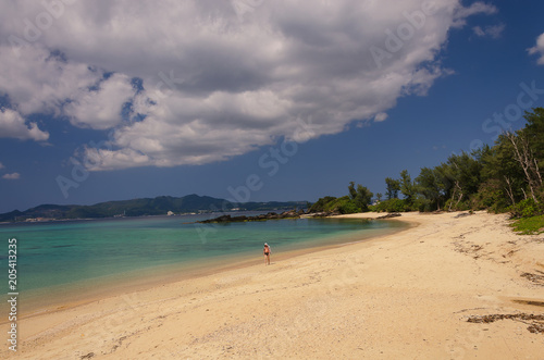 A man walking away on the beach of Kouki in Nago on the island of Okinawa in Japan. Beautiful turquoise water color of the South China sea.