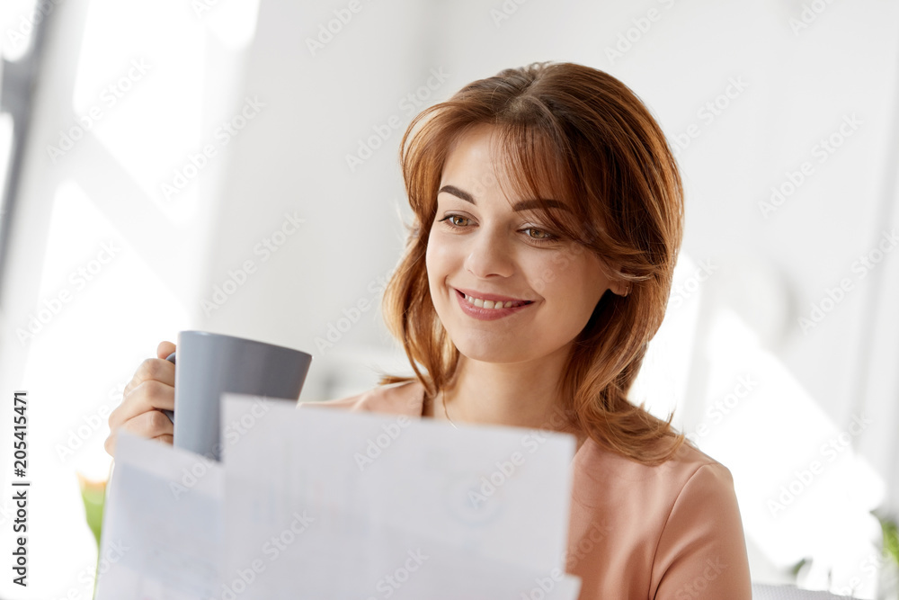business and people concept - businesswoman with papers at working office and drinking coffee business and people concept - businesswoman with papers at working office and drinking coffee