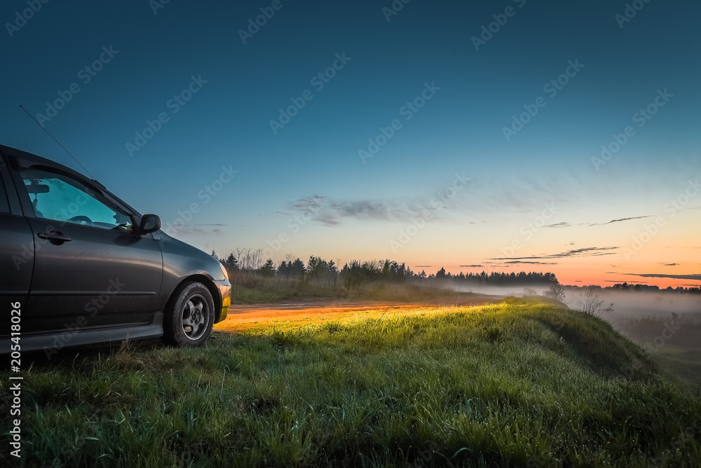 Car and light of headlights at sunset outdoors