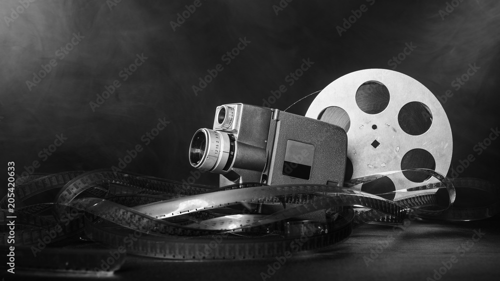 8 mm movie camera with a reel of film in smoke. black and white Stock Photo