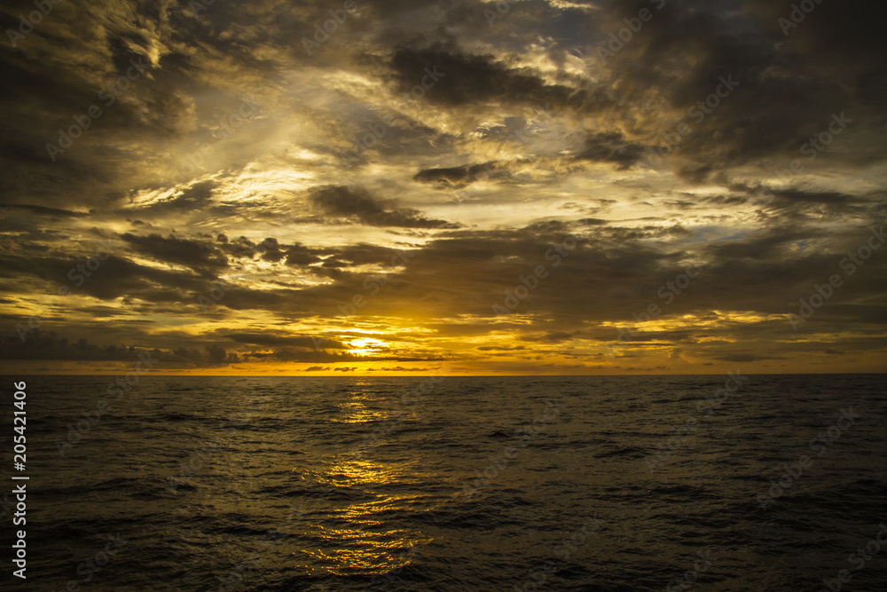 Naklejka premium Beautiful sunset on the ocean with a dramatic cloud and golden sunset sky 